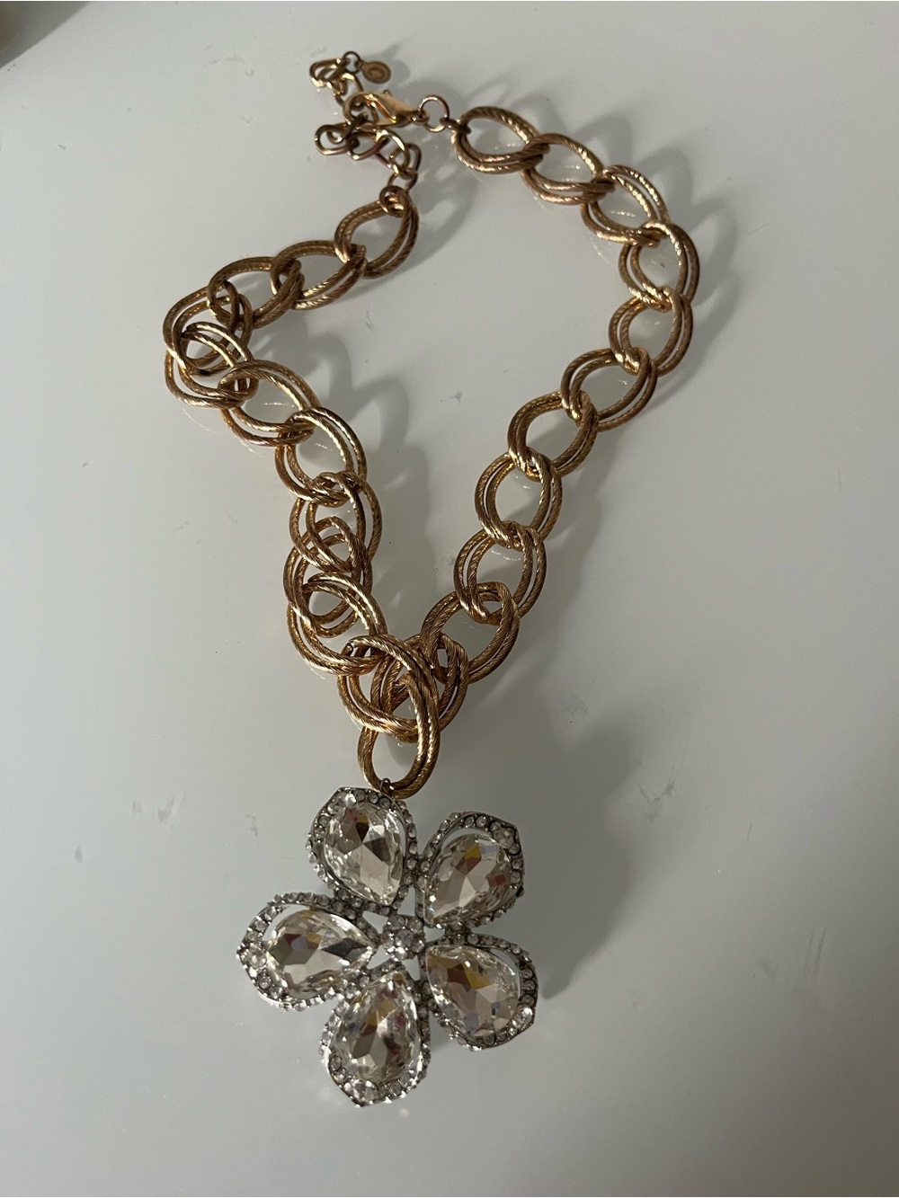 Gold necklace with rhinestone flower pendant.